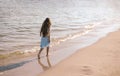 Back view of little girl with long hair in white dress walking on tropical beach vacation Royalty Free Stock Photo