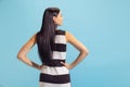 Back view of adorable young woman in summer striped dress posing isolated on blue background. Concept of beauty, art Royalty Free Stock Photo