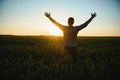 Back view of adult man farmer stand alone and look at sunset or sunrise in sky. Guy stand on wheat field. Ripe harvest Royalty Free Stock Photo