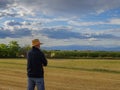 Back view of adult man farmer stand alone and look at sunset or sunrise in sky. Guy stand on wheat field. Ripe harvest time. Sun Royalty Free Stock Photo