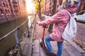 Back view of adult woman tourist with backpack discover Hamburg city on e-scooter. Most famous historic Speicherstadt