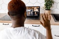 Back view of african american male freelancer waving hello to coworkers on video meeting, using laptop. Stylish friendly