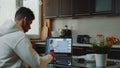 Back view of african man watching online video conference on computer and making notes