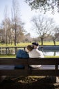 Back view of aged couple relaxing on bench in park