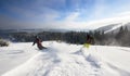 Male skiers freeriding on wide open mountain slope. Extremal skiing down between low fir trees. Panoramic mountain view. Royalty Free Stock Photo