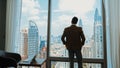 Ambitious businessman standing in ornamented office on cityscappe background