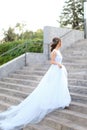 Back view of american bride walking on concrete stairs and wearing white dress. Royalty Free Stock Photo