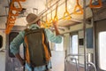 Back view of Asian backpackers holding handrail inside the train