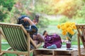 Back view of Asian senior woman sitting on garden chair and by the table in garden. Summer vacation in green surroundings. Happy Royalty Free Stock Photo