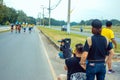 Back view of Asian sport photographer with camera sit to take picture marathon runners in running event marathon run on city