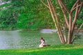 Back view of Asian woman with artificial bouquet sit to relax near pond in garden. Summer vacation in green surroundings.Happy