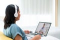 Back view of Asian woman making video call with her doctor with her feeling sick on laptop in bedroom for online healthcare
