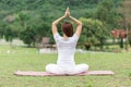 Back of view Asian woman sitting on yoga mat practice lotus pose with yoga meditation relax and refresh health on green grass feel Royalty Free Stock Photo