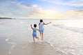 Back view Asian young sister and little brother having fun running together on tropical sand beach. Happy family boy and girl Royalty Free Stock Photo