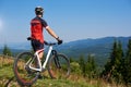Back view of athletic cyclist stopped on top of hill to enjoy beautiful view of distant mountains Royalty Free Stock Photo