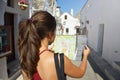 Back view of attractive beautiful brunette looking to her map in cozy street of Alberobello, South Italy. Travel concept.