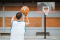 back view of a basketball player holding the ball while jump shot into the hoop Royalty Free Stock Photo