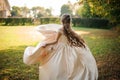 Back view of a beautiful bride spinning in a wedding dress dancing on the green field Royalty Free Stock Photo