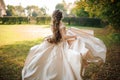 Back view of beautiful bride spinning in a wedding dress dancing on the green field Royalty Free Stock Photo