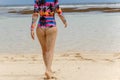 Back view of beautiful girl in a bathing suit walking on the beach with white sand Royalty Free Stock Photo