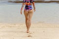 Back view of beautiful girl in a bathing suit walking on the beach with white sand Royalty Free Stock Photo