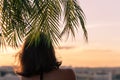 Back view of a beautiful girl in a straw hat against the background of the sea in branches of palm trees. Sunset beach. Summer Royalty Free Stock Photo