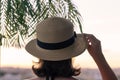 Back view of a beautiful girl in a straw hat against the background of the sea in branches of palm trees. Sunset beach. Summer Royalty Free Stock Photo