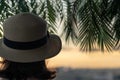 Back view of a beautiful girl in a straw hat against the background of the sea in branches of palm trees. Sunset beach. Summer Royalty Free Stock Photo