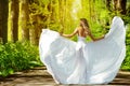 Back view of Beautiful Girl in White Dress Outdoors. Happy Woman in Wedding Gown walking away in Sunshine Park Alley. Carefree Royalty Free Stock Photo