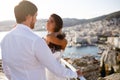 Back view of a beautiful just married couple, wearing in white clothing, with back panorama of city, wedding in Greece. Royalty Free Stock Photo