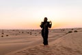 Back view of Beautiful mysterious woman in traditional arabic black long dress stands in the desert on sunset Royalty Free Stock Photo