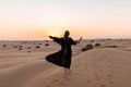 Back view of Beautiful mysterious woman in traditional arabic black long dress stands in the desert on sunset Royalty Free Stock Photo