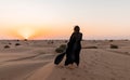 Back view of Beautiful mysterious woman in traditional arabic black long dress stands in the desert on sunset Royalty Free Stock Photo