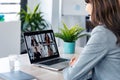 Beautiful young business woman making video call with computer while talking with earphone sitting in modern startup office Royalty Free Stock Photo