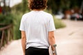 Back view of beautiful young woman in white t-shirt holding skateboard Royalty Free Stock Photo