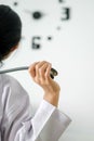 Behind young female doctor holding stethoscope standing and hand up for relaxing after finish work with clock on the wall. Royalty Free Stock Photo