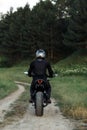 Back view of biker driving motorcycle in sunset on the country road. Royalty Free Stock Photo