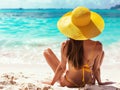 Back view of bikini girl happy carefree woman relaxing sitting in sand enjoying tropical beach destination