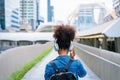 Back view of black student girl wearing headset and using mobile smartphone Royalty Free Stock Photo