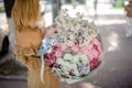 Back view of blonde woman holding a big bouquet of various flowers