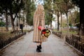 Back view of blonde woman walking with a bouquet of flowers in the park