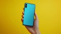 Back view of a blue smartphone held in a hand with yellow background Royalty Free Stock Photo