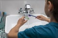 Back view of boy cleaning his dental orthodonic plates with  toothbrush. Royalty Free Stock Photo