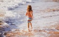 Back view of boy running beach near the seaside. Excited amazed kid having fun with running through water in ocean or Royalty Free Stock Photo