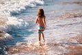 Back view of boy running beach near the seaside. Excited amazed kid having fun with running through water in ocean or Royalty Free Stock Photo