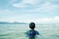 Back view of boy swimming in sea in background of blue sky Royalty Free Stock Photo