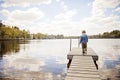Back view of boy walking on dock in lake Royalty Free Stock Photo