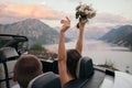 Back view of bride and groom in cabriolet car with hands raised Royalty Free Stock Photo