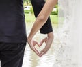 Back view of bride in white dress and groom in suit holding hands heart shape earnestly wedding theme Royalty Free Stock Photo