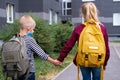 Back view Brother and sister going school after pandemic over. Kids wearing mask and backpacks protect and safety from Royalty Free Stock Photo